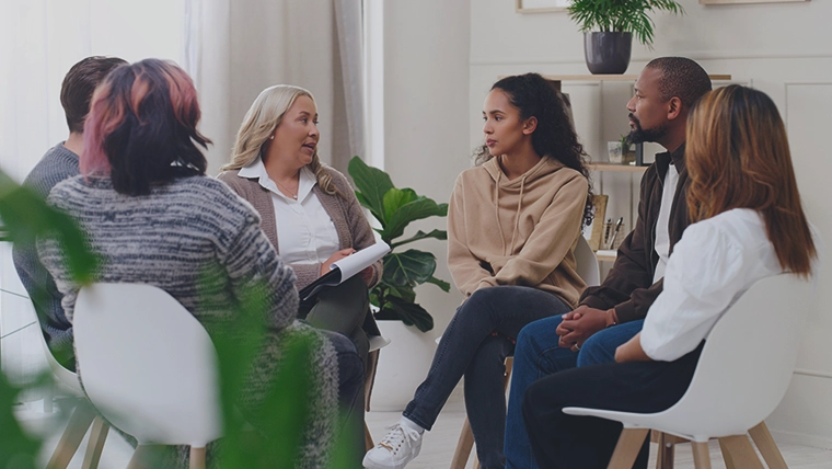 Employees sat on chairs, in a circle, discussing workplace wellbeing and wellness